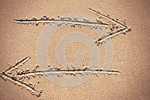 Two arrow signs drawing in sand background