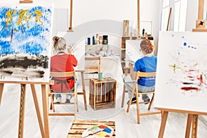 Two artist student women on back view painting at art school