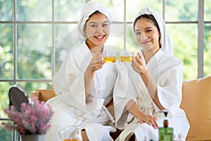 Two Asian beautiful girl hold cup of tea and look to camera after massage or spa with happy and relax emotion with day light