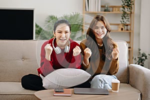 Two asian beauty smiling young women sitting on sofa Attractive casual girl feel happy and relax,having fun watch comedy video on