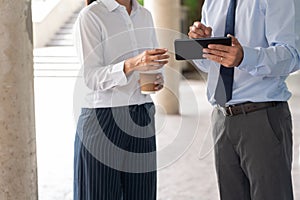 Two asian business coworkers outside office buildings discuss and commenting work to each other