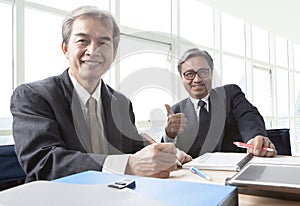 two of asian business man toothy smiling face ,relaxing in office life