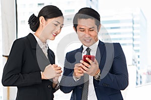 Two asian business people smiling and having fun chit chat in workplace office