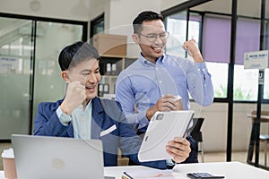 Two Asian businessmen raising their hands to celebrate success, rejoicing in increasing profits