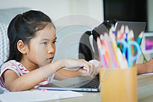 Two asian child girl students study online with teacher by video call together. Siblings are homeschooling with computer laptop