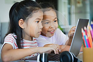 Two asian child girl students study online with teacher by video call together. Siblings are homeschooling with computer laptop
