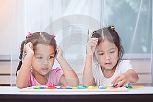 Two asian child girls having fun to play and learn magnetic alphabet