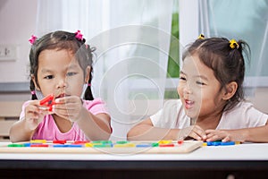 Two asian child girls having fun to play and learn magnetic alphabet