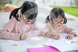 Two Asian Children Doing Homework Together at home