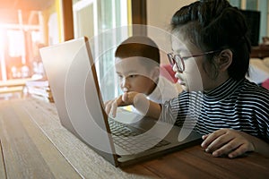 two asian children learning to use computer laptop at home living room