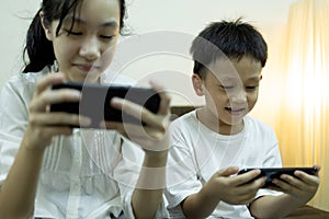 Two asian children people use smart phone and smile happily,sibling is relaxing enjoying,child girl playing online games on phone,