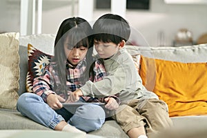 two asian children playing computer game using digital tablet