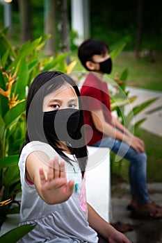 Two Asian children wearing mask standing distance of 1 meter from others keeping distancing. To protect from COVID-19 viruses and