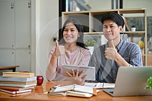 Two Asian college students are showing their thumbs up while studying