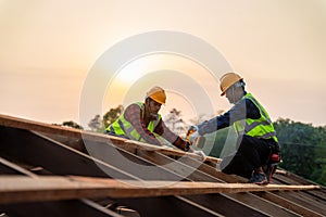 Two asian construction worker install new roof, Roofing tools, Electric drill used on new roofs of wooden roof structure, Teamwork