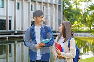 Two Asian couple university students walking and talking to class in walkway on a beautiful sunny day in campus