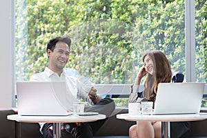 Two asian coworkers use laptop work together having coffee in af