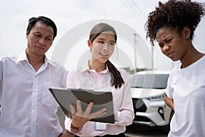 Two Asian driver Talk to Insurance Agent for examining damaged car and customer checking on report claim form after an accident.