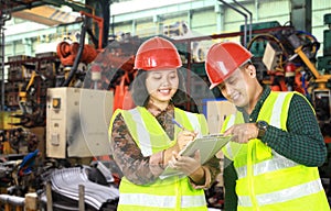 Two asian engineer writing on a clipboard in a factory