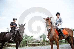 two asian equestrian athletes riding their respective horses photo