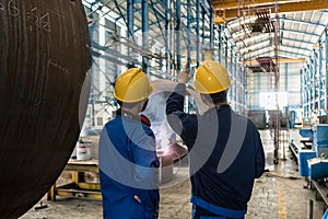 Two Asian experts talking while supervising fabrication