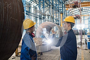 Two Asian experts talking while supervising fabrication