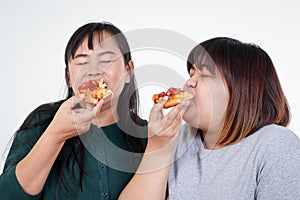 Two Asian fat women are eating pizza happily. But has a negative effect on the body.