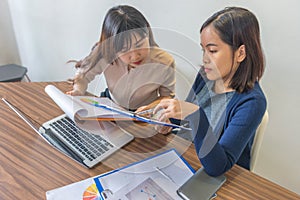 Two Asian female accountants working together on financial report document