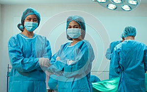 Two asian female doctors wearing mask and uniform crossed arms with confidence in hospital doing surgical operation to patient