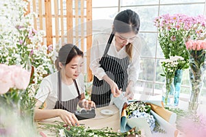 Two Asian female florists preparing and arranging and wrapping bouquet flowers