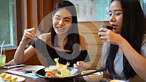 Two Asian female friends eating and having a meal together. Women enjoying good time at restaurant