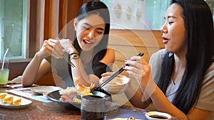 Two Asian female friends eating and having a meal together. Women enjoying good time at restaurant