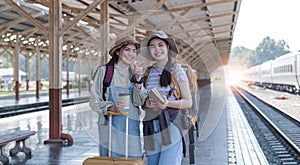 Two Asian female tourist friends are at the train station. Waiting for the train to travel to the provinces together on