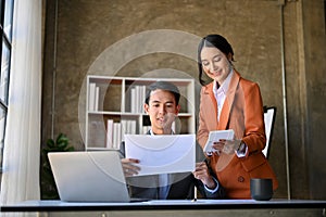 Two Asian financial analysts working on sales and financial investment report together