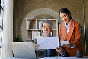 Two Asian financial analysts working on sales and financial investment report together