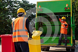 Two Asian Garbage men working together on emptying dustbins for trash removal. Garbage collector