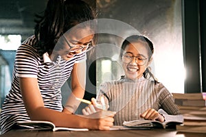 Two asian girl laughing with happiness emotion doing school home work in living room