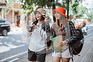 two Asian girls backpacking to find tourist destinations with cameras and maps