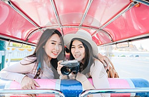 Two Asian girls best friends traveller sit in Tuk Tuk taxi