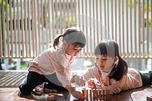 Two Asian girls playing wooden stacks at home