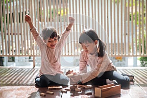 Two Asian girls playing wooden stacks at home