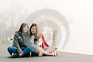 Two asian girls Very close friends Wearing a sweater, take a selfie phone, Along the road beside the reservoir in the thick fog Wi