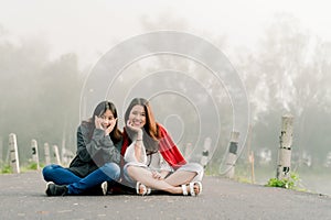 Two asian girls Very close friends Wearing a sweater In tourist attractions Along the road beside the reservoir in the thick fog