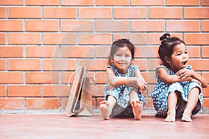 Two Asian girls who feel bored sitting and hugging their knees