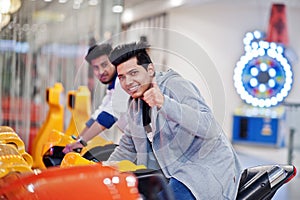 Two asian guys compete on speed rider arcade game motorcycle racing simulator machine photo