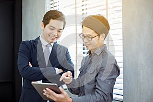 Two Asian handsome businessmen using touchpad with partners disc