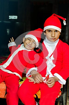 Two Asian Indian Ethnicity kids wearing Santa Hat waving having