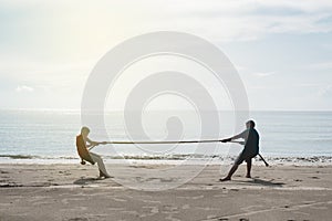 Two asian kids pulling a rope at the beach