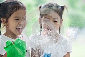 Two asian little child girls help parent to clean window