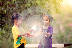 Two asian little girls having fun to play water together